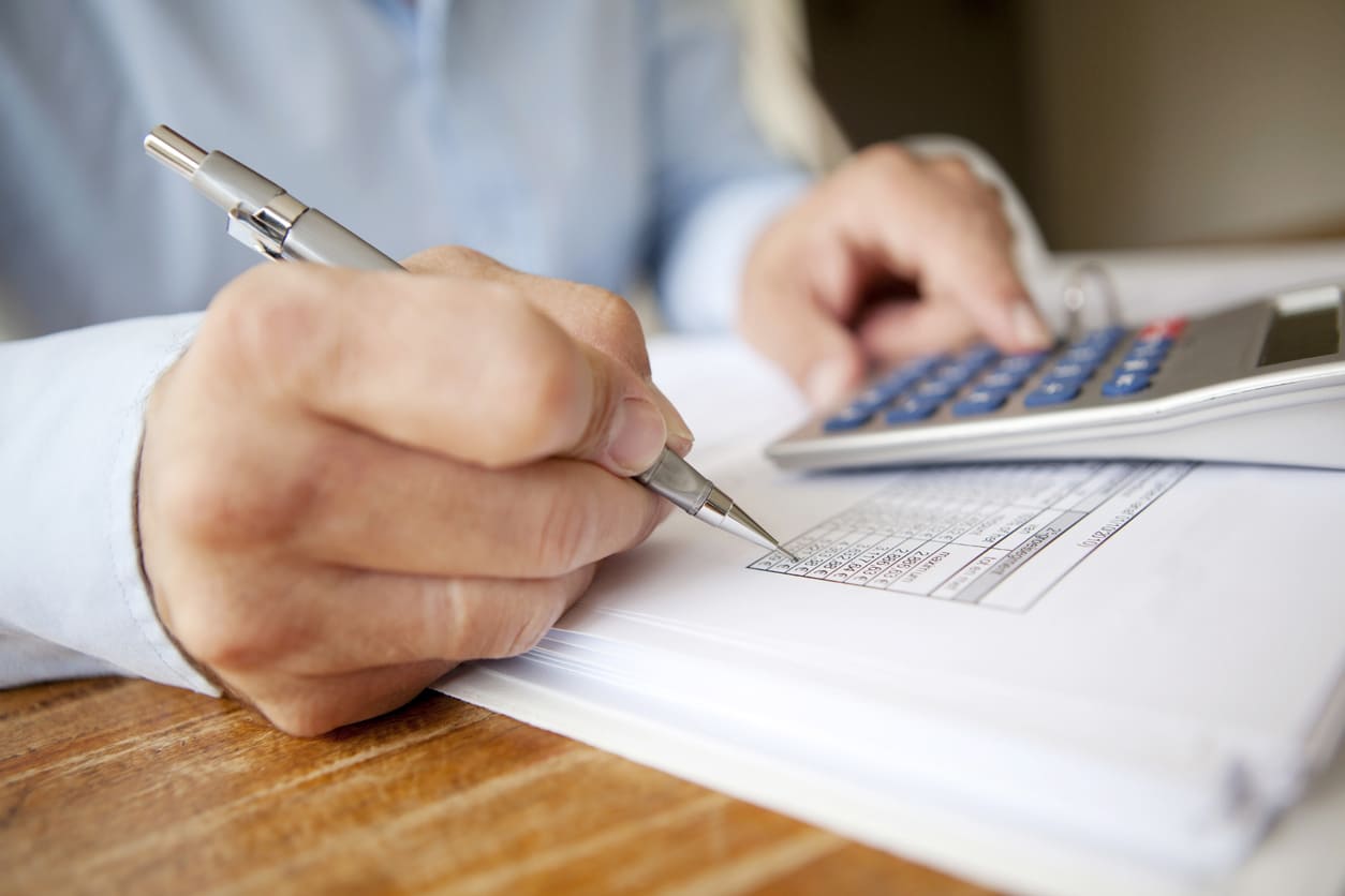 profissional de ciências contábeis analisando com calculadora, papel e caneta.