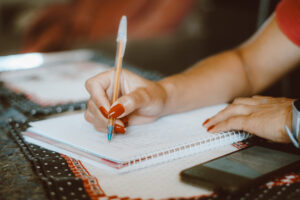 mulher escrevendo no caderno em cima da mesa