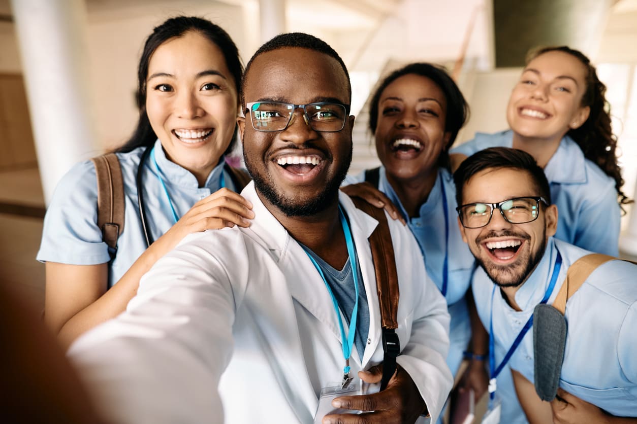 várias pessoas de diferentes etnias em uma residência médica na graduação de medicina.
