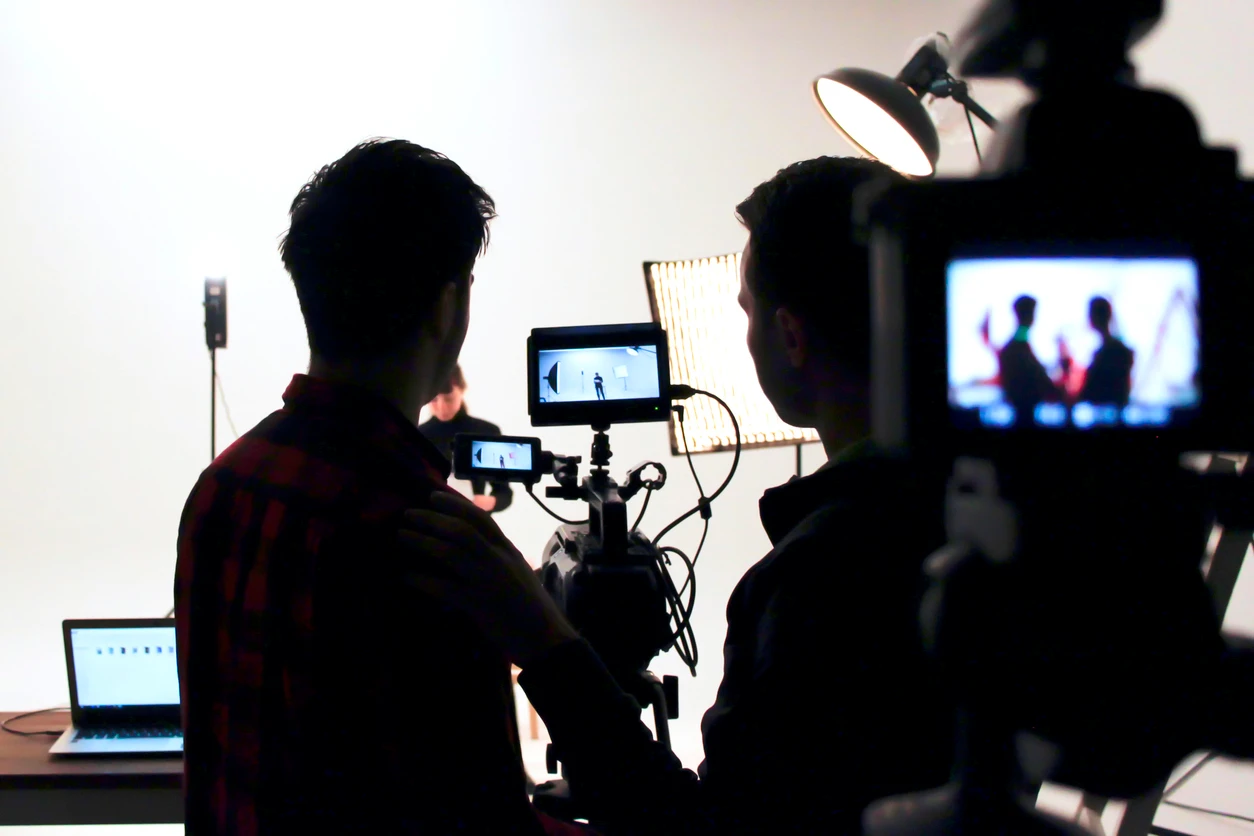 Equipe de produção gravando vídeo em estúdio com câmera profissional, iluminação e equipamento tecnológico